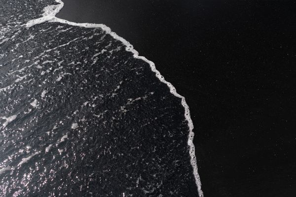 Picture of White ocean foam on black sand volcanic texture