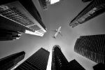 Picture of Tall city buildings and a plane flying overhead