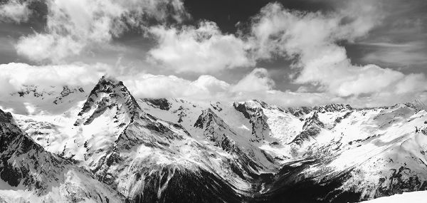 Picture of Black and white panorama of snowy winter mountain in sunlight clouds